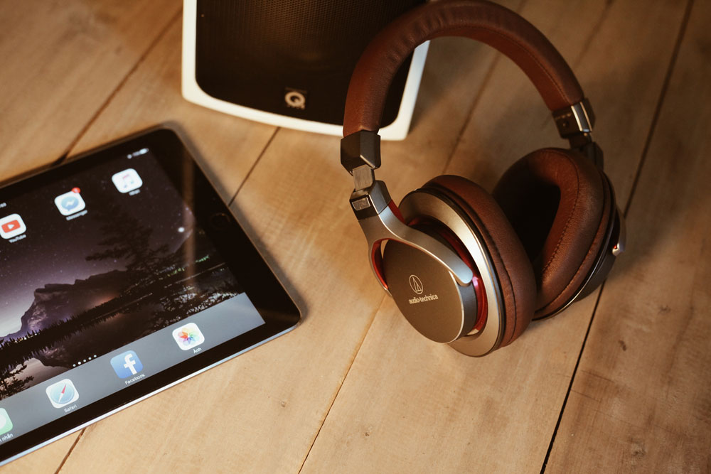 A pair of modern wireless Audio Technica headphones next to an iPad